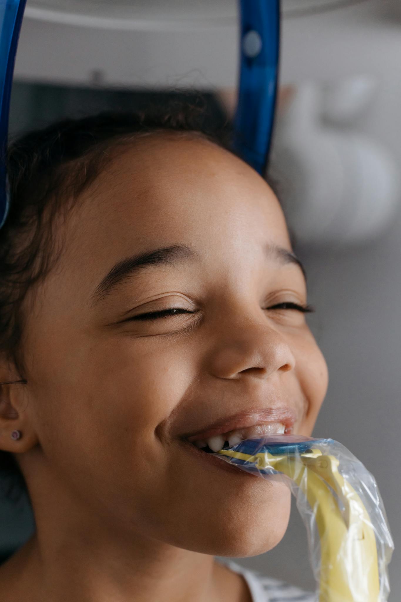 Smiling child undergoing dental x-ray at a clinic, emphasizing dental health and care.